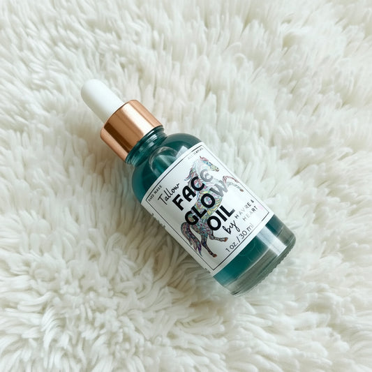 Bottle of 'Face Glow Oil' on a fluffy white surface